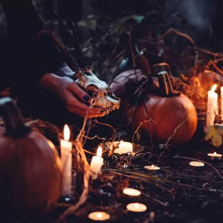 A low-lit Halloween-themed scene featuring iconic seasonal items, such as pumpkins, candles and skulls.