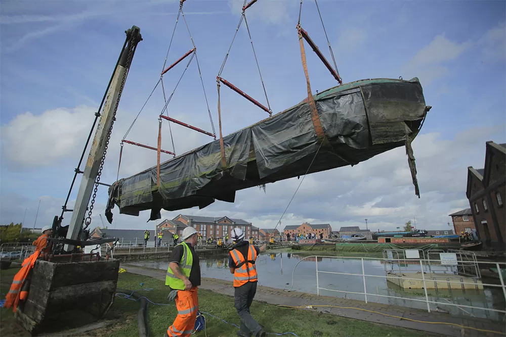 A watercraft being lifted from the dock at Ellesmere Port for transportation to restoration workshop nearby