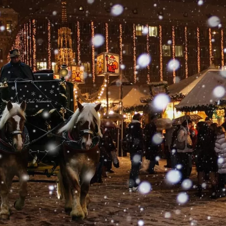 A horse-drawn cart passes a Christmas market in the snow
