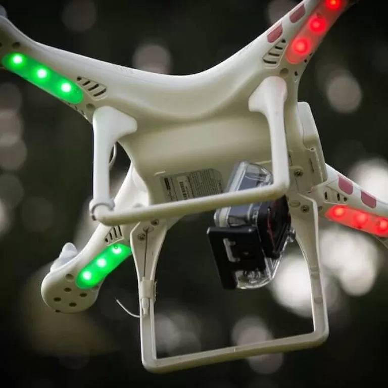 Low-angle shot of a drone in flight with a camera affixed to its body.