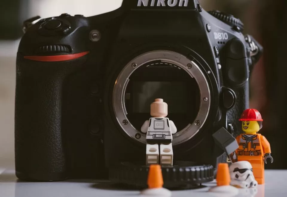 Lego minifigures photographed beside a Nikon DSLR camera.