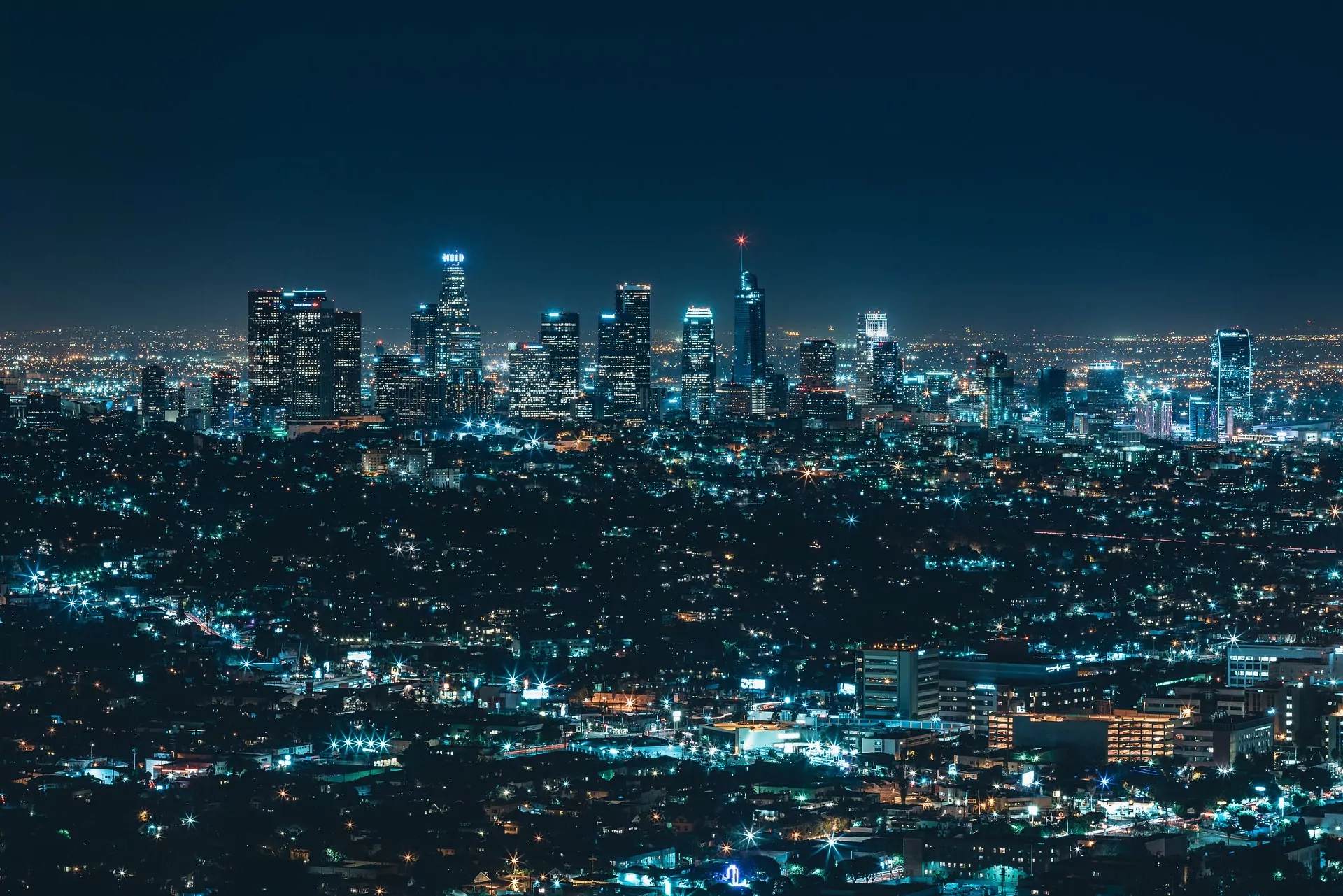An image of a city skyline at night. Clusters of high-rise buildings dominate this landscape and blue hued lights give this image a striking appearance. BBC's Panorama: 15 minute city.