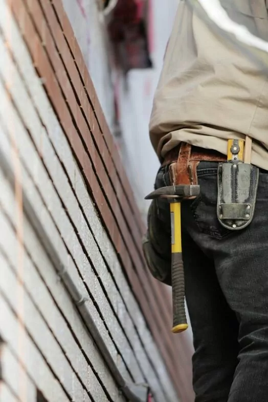 A builder on site discussing architectural plans. The camera is focused on his waist showing a number of tools hanging from a belt. The time-lapse of interior fit-outs.